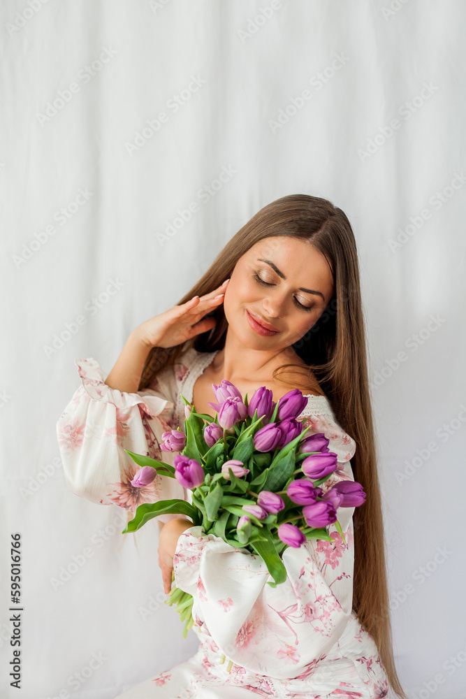 Portrait of sexy beautiful young woman with long hair. Model with a bouquet of lilac tulips on white. Spring. Holidays. Portrait of sexy beautiful young woman with long hair. Model with a bouquet of lilac tulips on white. Spring. Holidays.
