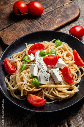 Spaghetti with feta cheese and tomatoes in a plate. Italian pasta
