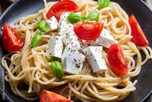 Spaghetti with feta cheese and tomatoes in a plate. Italian pasta photo