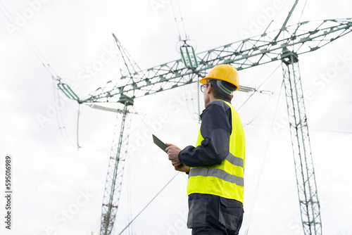 Engineer with digital tablet on a background of power line tower