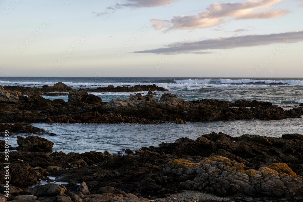 Obraz premium Sandy beach, with rocky outcroppings at the shoreline at sunset in Franzkraal, South Africa