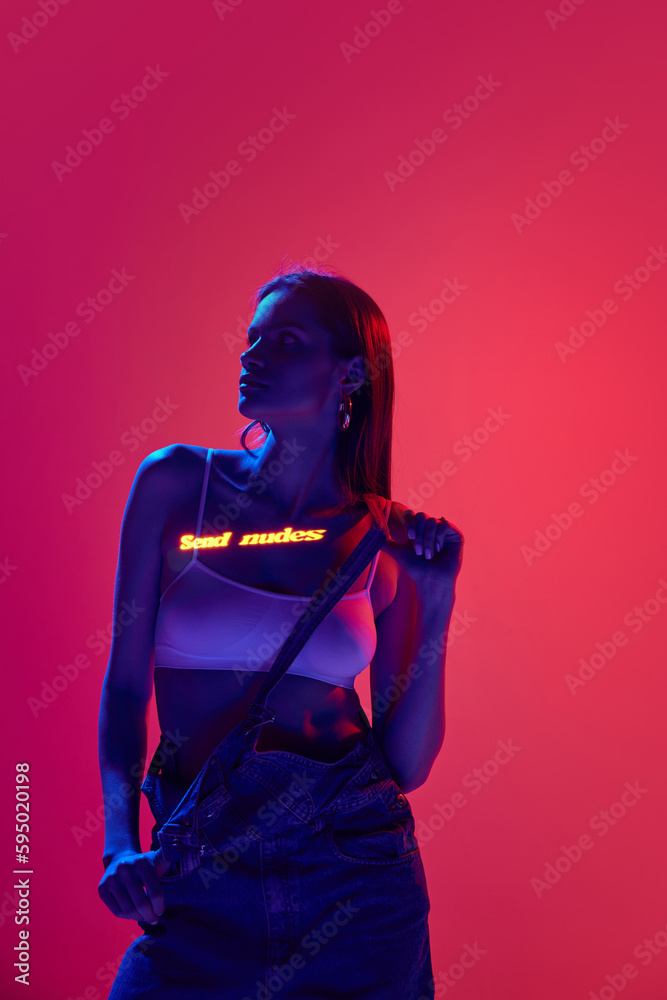Sensual cyberpunk girl with long hair and digital neon filter lights on body on red and pink background. Internet dating