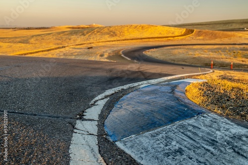 View of a curved dirt road illuminated by the rising sun in Thunderhill Raceway Park, CA