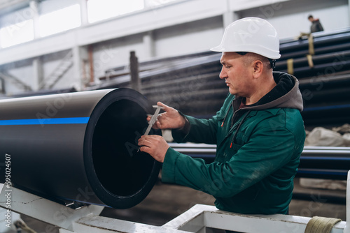 An engineer measures the thickness of a newly manufactured pipe.