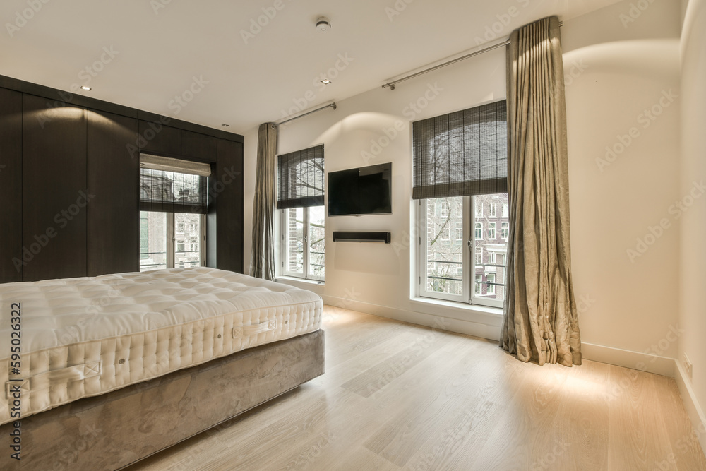 Fototapeta premium a bedroom with wood flooring and large windows that look out onto the street in front of the apartment building