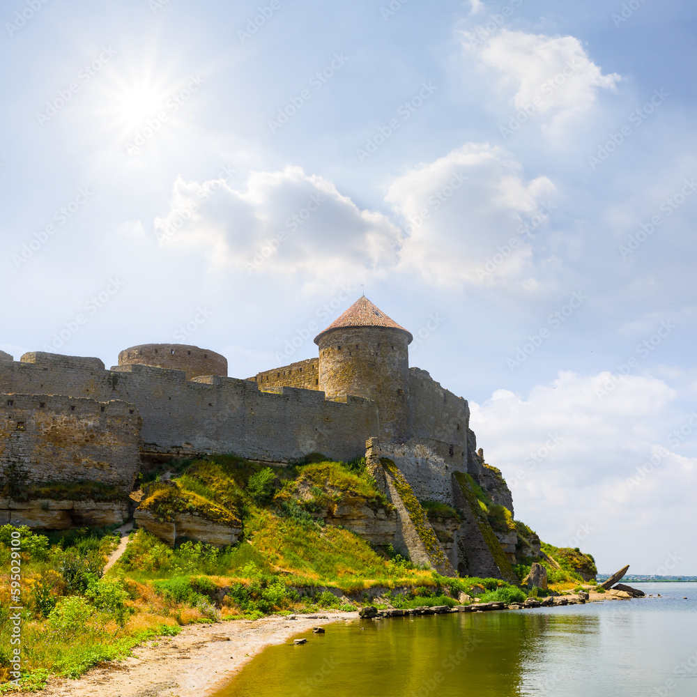 old medieval castle on river coast under blue cloudy sky
