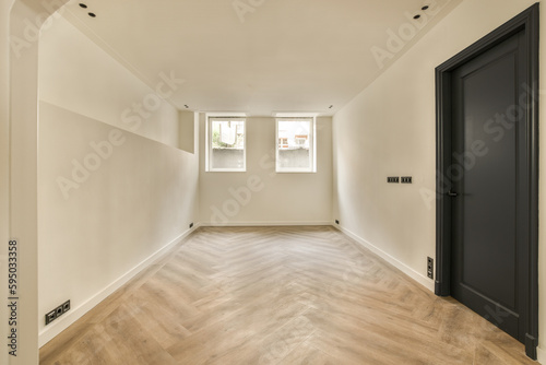 an empty room with wood flooring and white walls  there is a black door leading to the left side