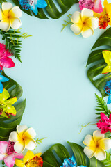 Summer background with tropical orchid flowers and green tropical palm leaves on light background. Flat lay, top view.