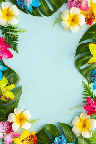 Summer background with tropical orchid flowers and green tropical palm leaves on light background. Flat lay, top view.