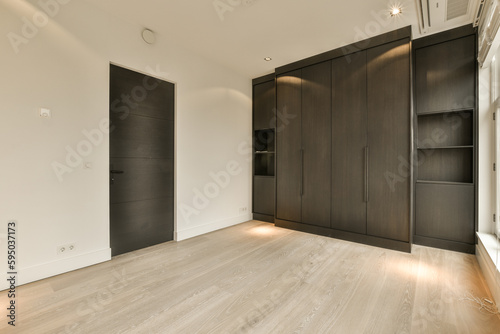 an empty room with wood flooring and black wardrobes on either side by the wall, there is no one in it