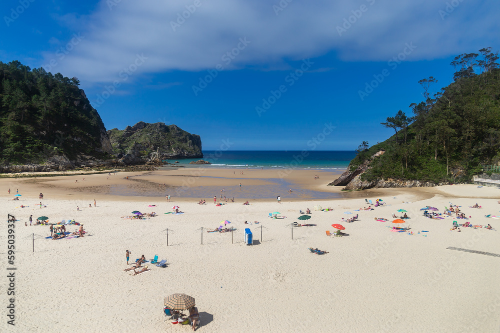 Fototapeta premium Sunny beach with people on the sand and in the sea