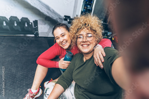Two beautiful, overweight women determined to achieve their goals and inspire others along the way at the gym. Doing selfie.