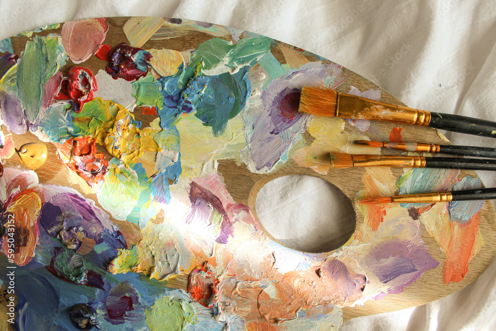 Fototapeta premium Palette and brushes photo on the white blanket. Art, aesthetic sunny vibe, spring, summer mood.