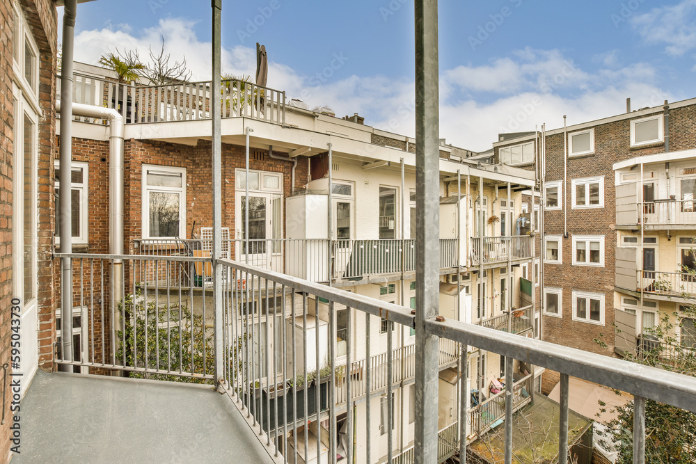 Fototapeta premium a balcony with some buildings in the background and a blue sky above it, taken from an apartment balcony railing