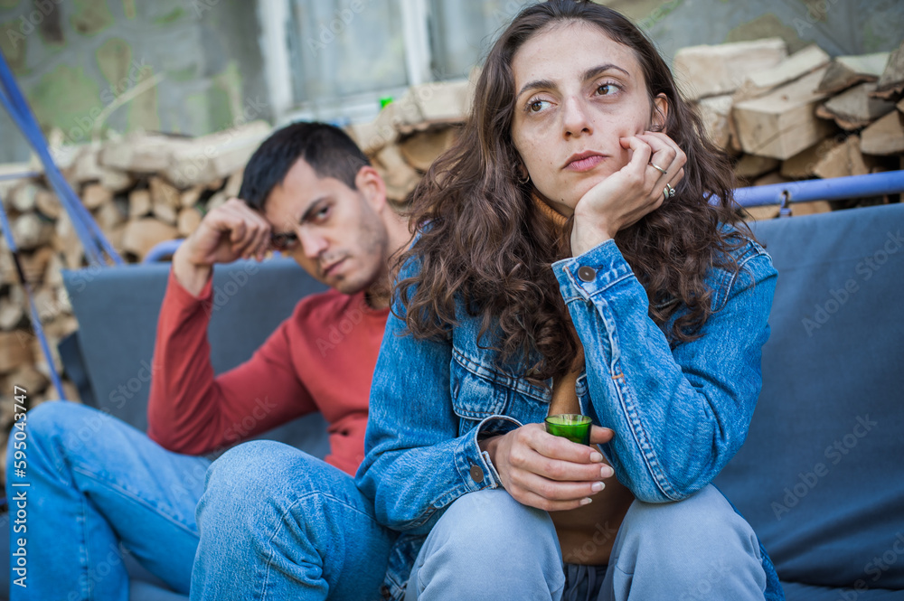 Very drunk couple, a boy and a girl, drink a strong alcoholic drink from small glasses. Bad social unhappy atmosphere Very drunk couple, a boy and a girl, drink a strong alcoholic drink from small glasses. Bad social unhappy atmosphere