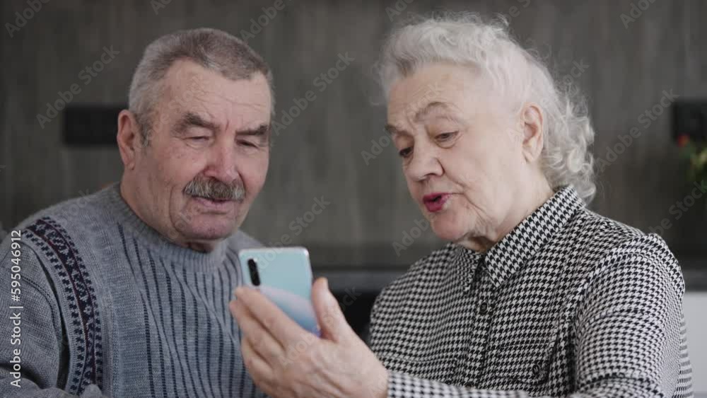 An elderly couple talking on their smartphone by video link. A man and a woman in their eighties An elderly couple talking on their smartphone by video link. A man and a woman in their eighties