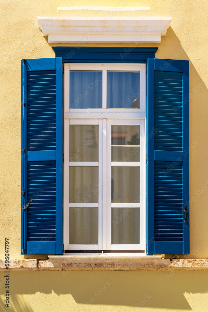Fototapeta premium Window with blue shutters. European yellow house facade. 