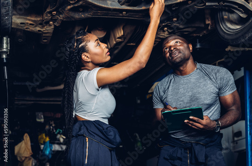 Professional Car Mechanic is Investigating Under a Vehicle on a Lift in Service. Auto Service Worker Checking Car Under Carriage Look For Issues. Car service technician check and repair customer car.