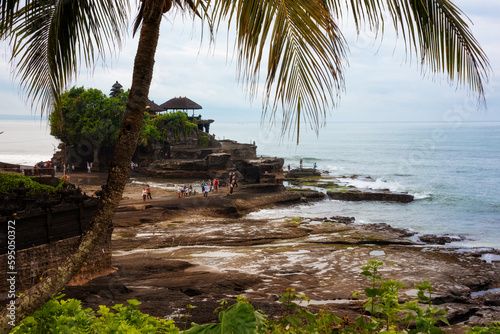 Tanah lot hindu temple seen from a palm tree on Bali island  Indonesia