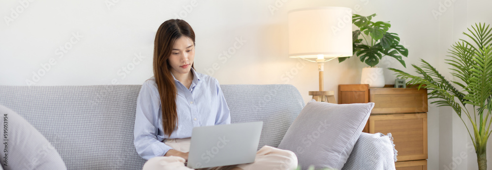 Woman using laptop to work or do homework at home with smiling face in her living room, Creating happiness at work with a smile, Live performance or video call with laptop, Work from home. Woman using laptop to work or do homework at home with smiling face in her living room, Creating happiness at work with a smile, Live performance or video call with laptop, Work from home.