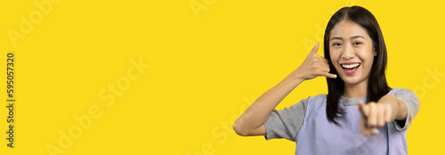 Call sign, Bright young asian woman inviting to call isolated on yellow background, Suggest to call or invite to apply for membership, Isolated on yellow background.. © Puwasit Inyavileart