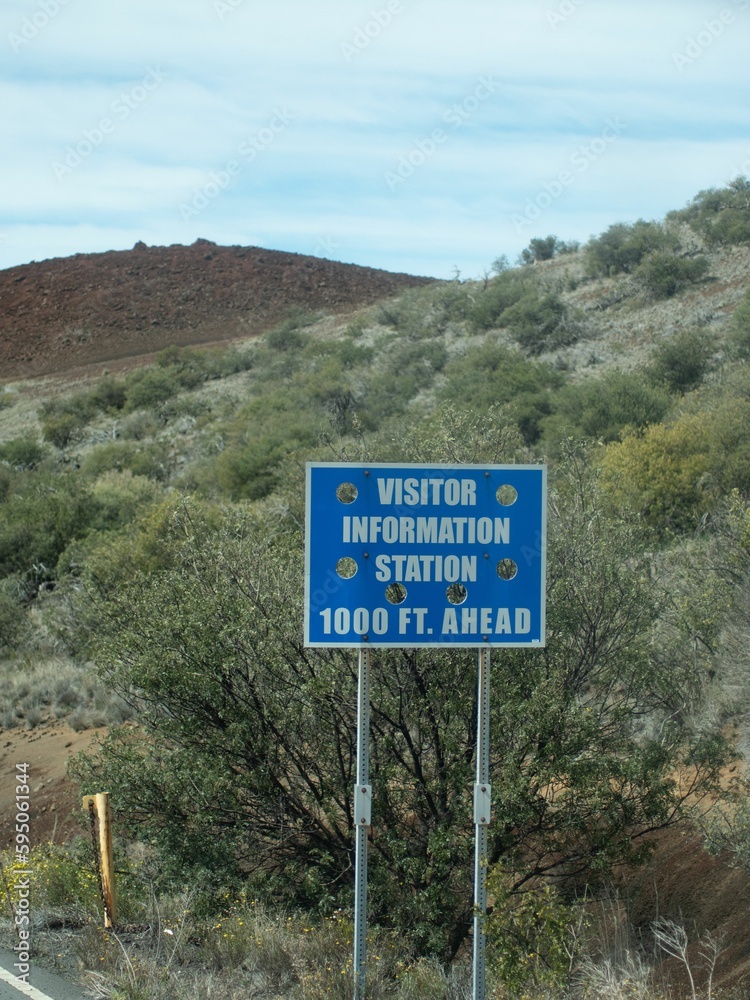 Blue informational signpost on the side of a road, providing travelers with directions