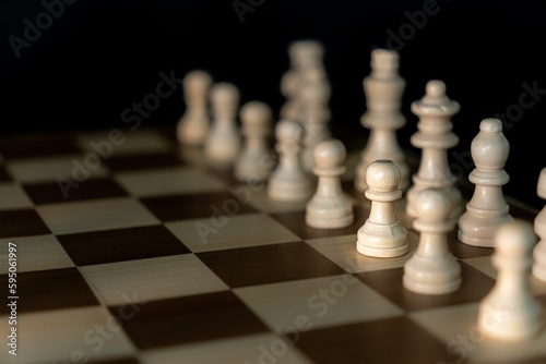 Closeup of a chessboard set up in its beginning position featuring classic white chess pieces
