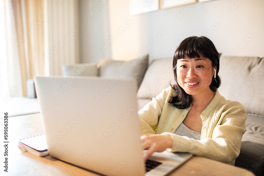 Young Japanese Woman using a laptop on a couch Young Japanese Woman using a laptop on a couch