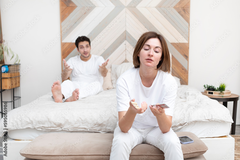 Frustrated and depressed woman sitting on the edge of the bed after conflict with her husband because of his erectile dysfunction problem Frustrated and depressed woman sitting on the edge of the bed after conflict with her husband because of his erectile dysfunction problem