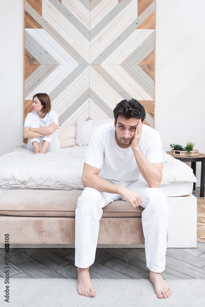 Frustrated and depressed man sitting on the edge of the bed after conflict with his wife because of his erectile dysfunction problem Frustrated and depressed man sitting on the edge of the bed after conflict with his wife because of his erectile dysfunction problem