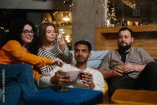 A group of friends eat snacks and drink beer while watching TV.