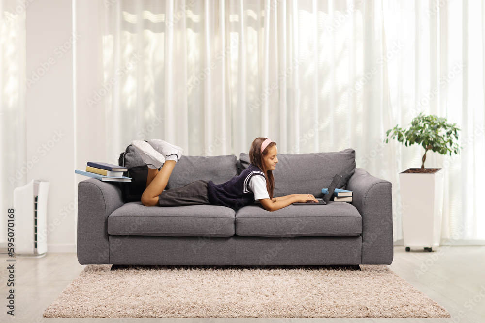 Child laying on a sofa and using a laptop computer at home Child laying on a sofa and using a laptop computer at home