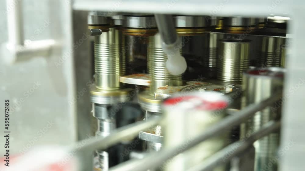 Tomato sauce cans filling machine in a canned food production facility Tomato sauce cans filling machine in a canned food production facility