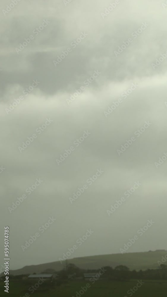 A timelapse video of the cloudy sky over the green hills of Ireland. The clouds change color and intensity as they move in the sky. Vertical video. A timelapse video of the cloudy sky over the green hills of Ireland. The clouds change color and intensity as they move in the sky. Vertical video.