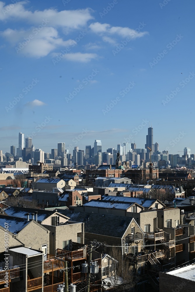 a large city skyline viewed over buildings and a blue sky