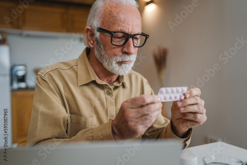 One man senior caucasian male hold medicine drugs tablet read label