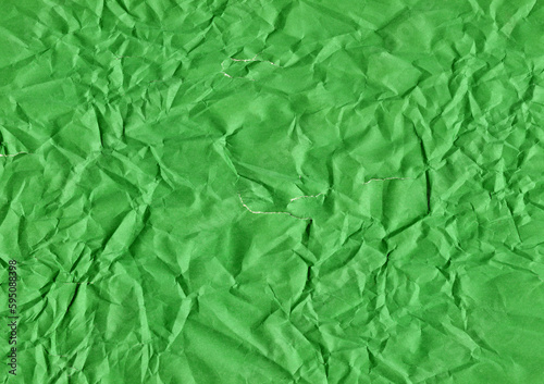 Cracks and tears on a green crumpled sheet of paper
