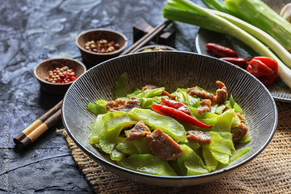 Celtuce (stem lettuce, Lactuca sativa var augustana ) stir fried with some meat and spices on table - Chinese cuisine