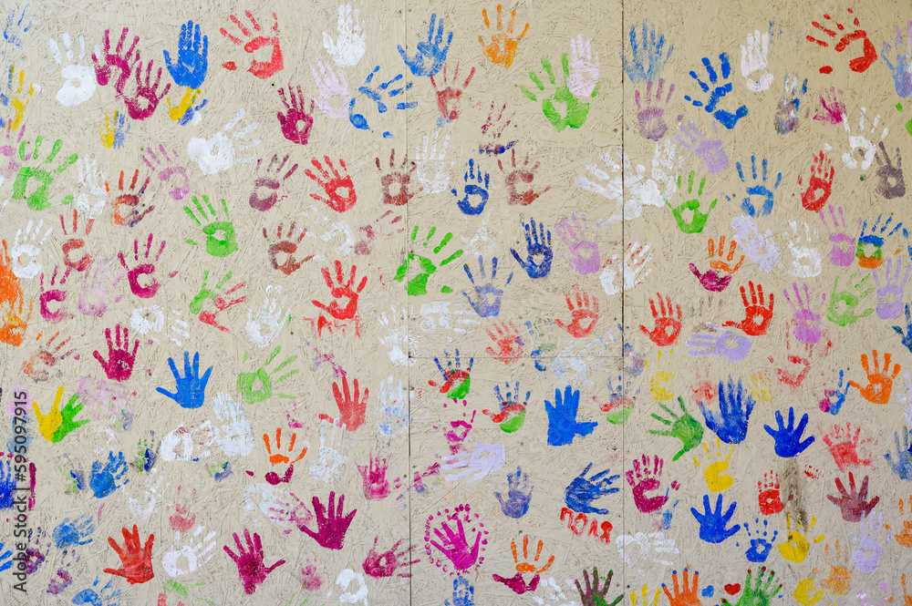 Fototapeta prints of children's hands in multi-colored paint on the wall
