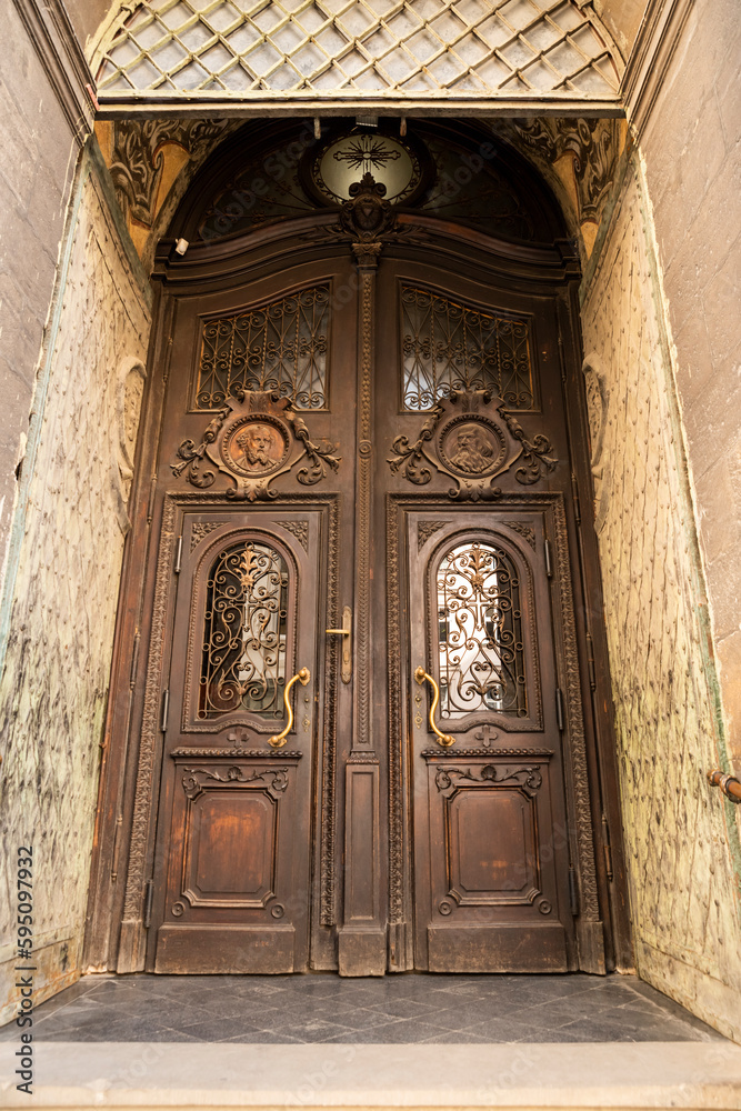 Entrance street carved wooden doors with metal inserts and hinges