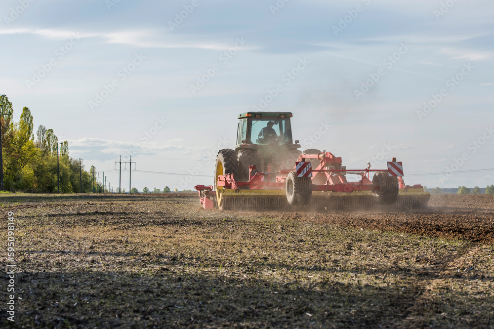 Fototapeta premium tractor during sowing in an open field on a sunny day