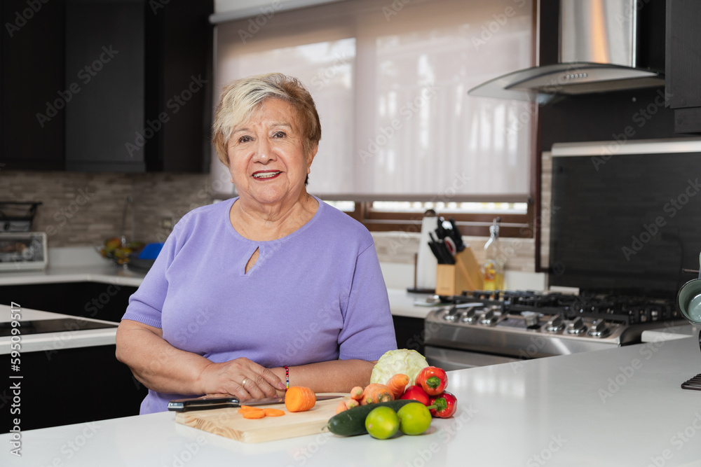 Happy grandmother in her kitchen - elderly woman cooking healthy food in her kitchen Happy grandmother in her kitchen - elderly woman cooking healthy food in her kitchen
