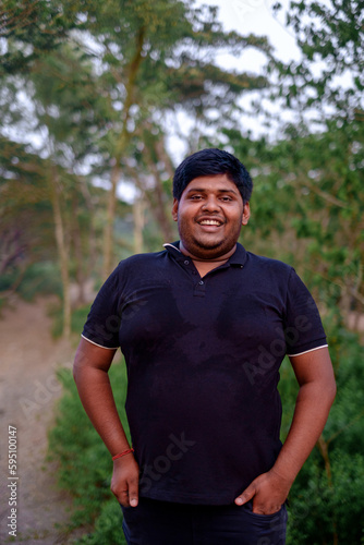 South asian overweight young man standing within green natural environment photo