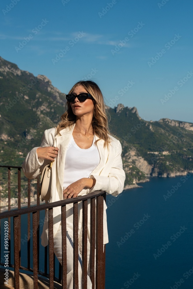 Stylish young woman posing against the background of the blue sea and mountains. Ravello, Italy. Stylish young woman posing against the background of the blue sea and mountains. Ravello, Italy.