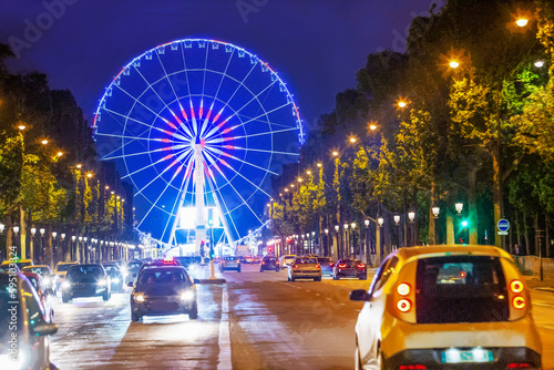 ferris wheel on Place dela Concorde (view from Champ Elysees street with lights of cars and illuminated city in night)