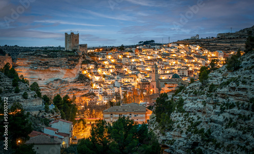 Panoramic view at dawn of Alcalá de Júcar, Albacete, Spain, with illumination of streetlights and castle in the upper part of the town