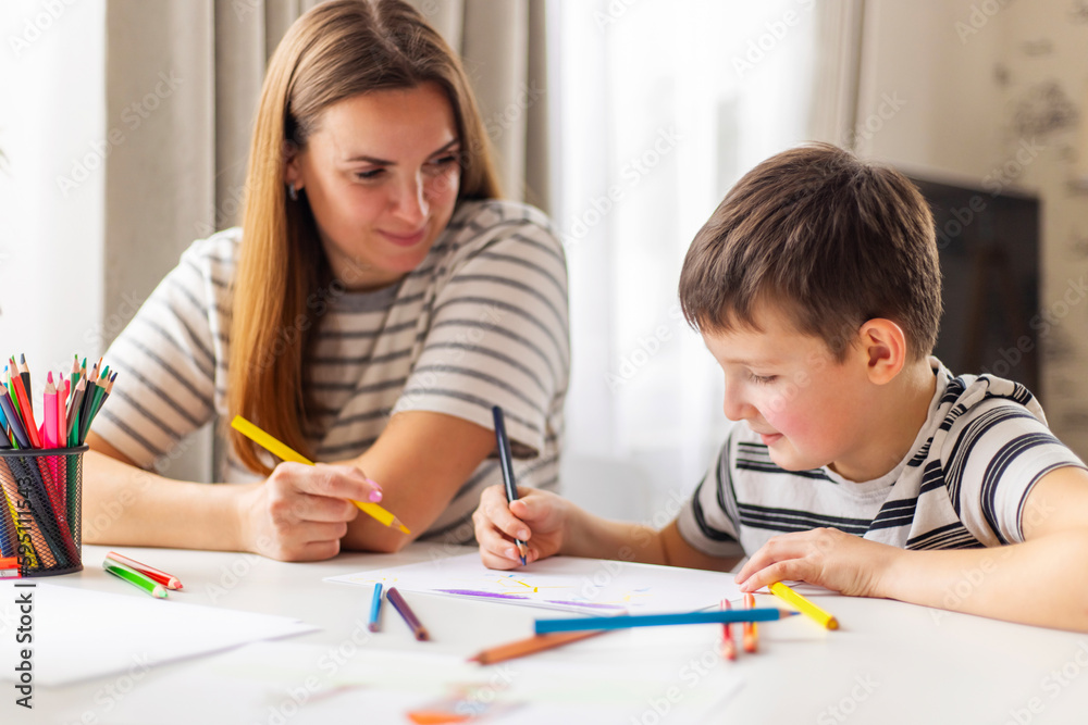 Mother and child drawing with pencils sitting at the desk at home Mother and child drawing with pencils sitting at the desk at home