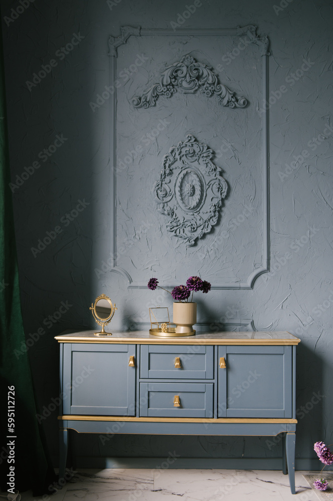 Vintage chest of drawers decorated with flowers in the interior with stucco on the wall, luxury home design