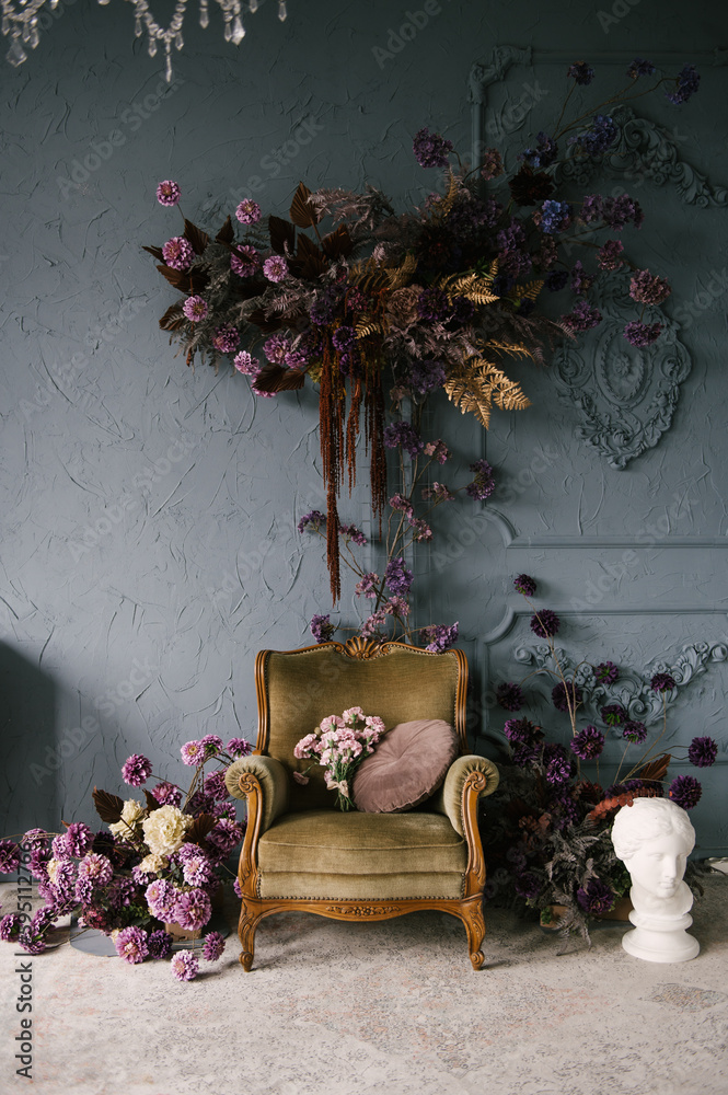Vintage wooden armchair decorated with flower arrangements in the interior, luxury home design