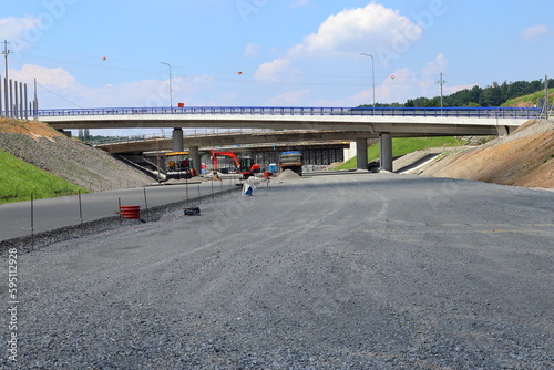 Construction of a new highway. Bridge over the road. Red excavator, truck.Sunny day. photo